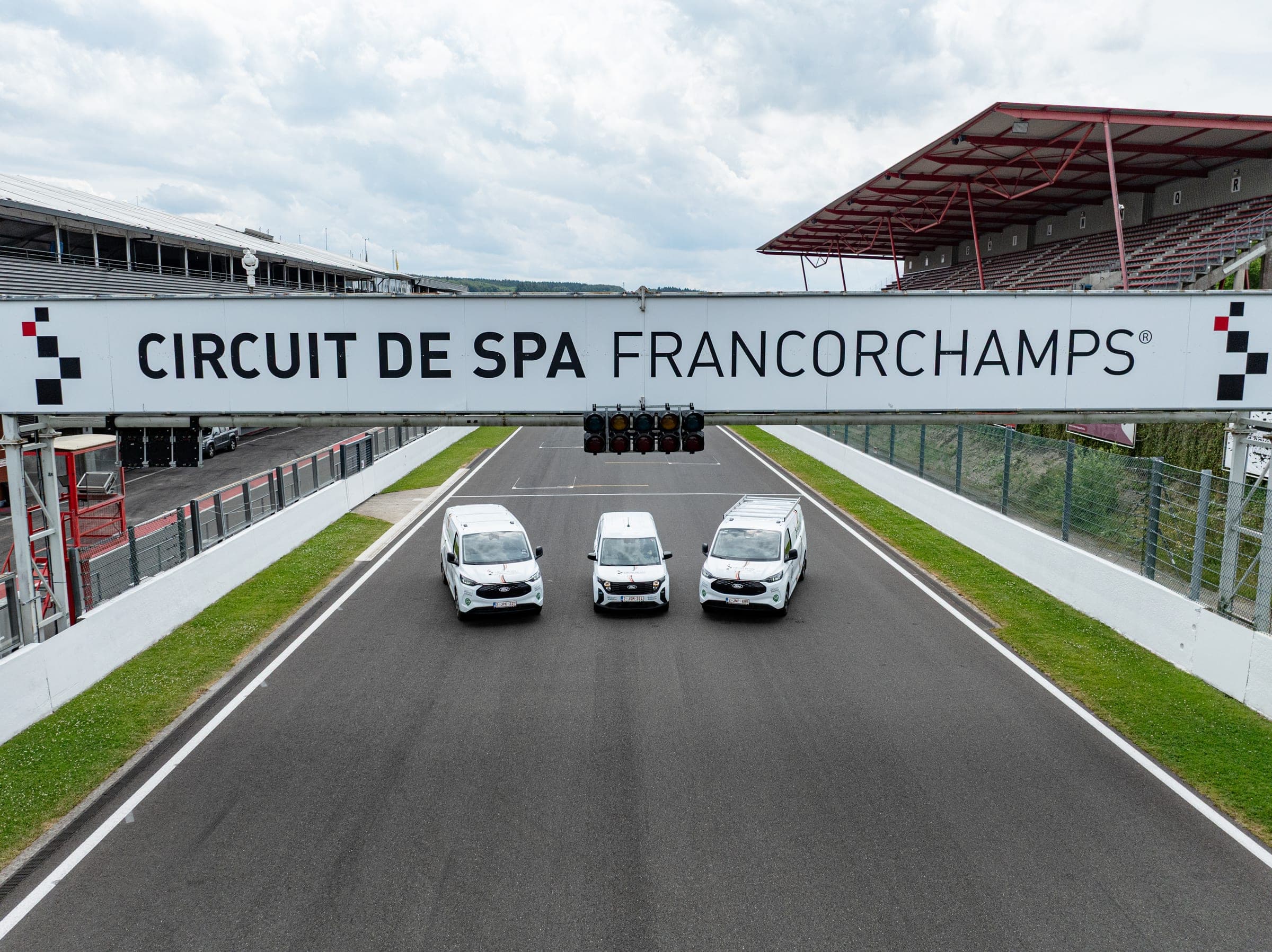 Les trois utilitaires aménagés par Amecam alignés sous le portique Circuit de Spa-Francorchamps, vue aérienne